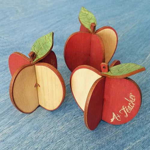 Doles Orchard laser-cut 3d apple ornaments on a blue wood background featuring the text "A+ Teacher" in script