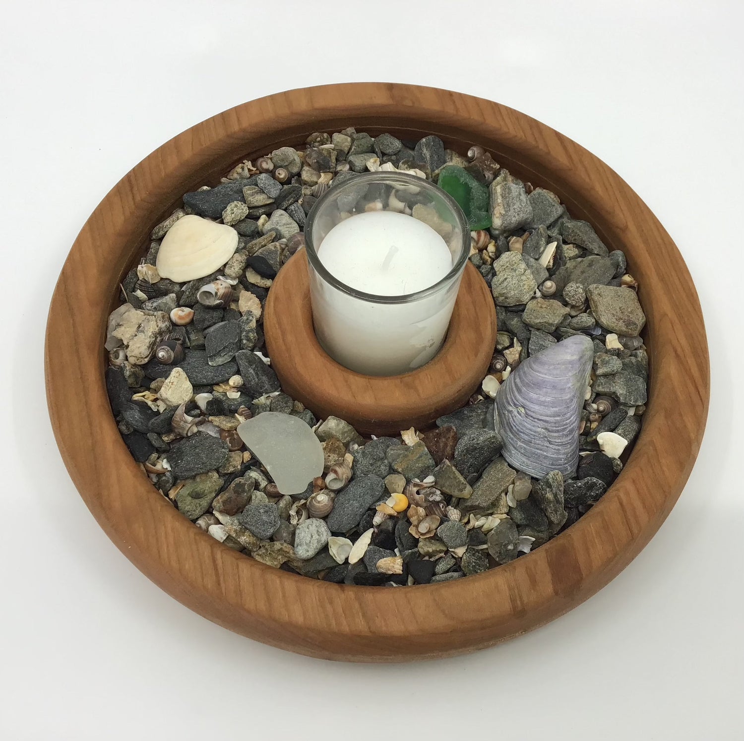 Moshier Island Woodworks' solid cherry wooden candle votive with small candle among rocks and shells